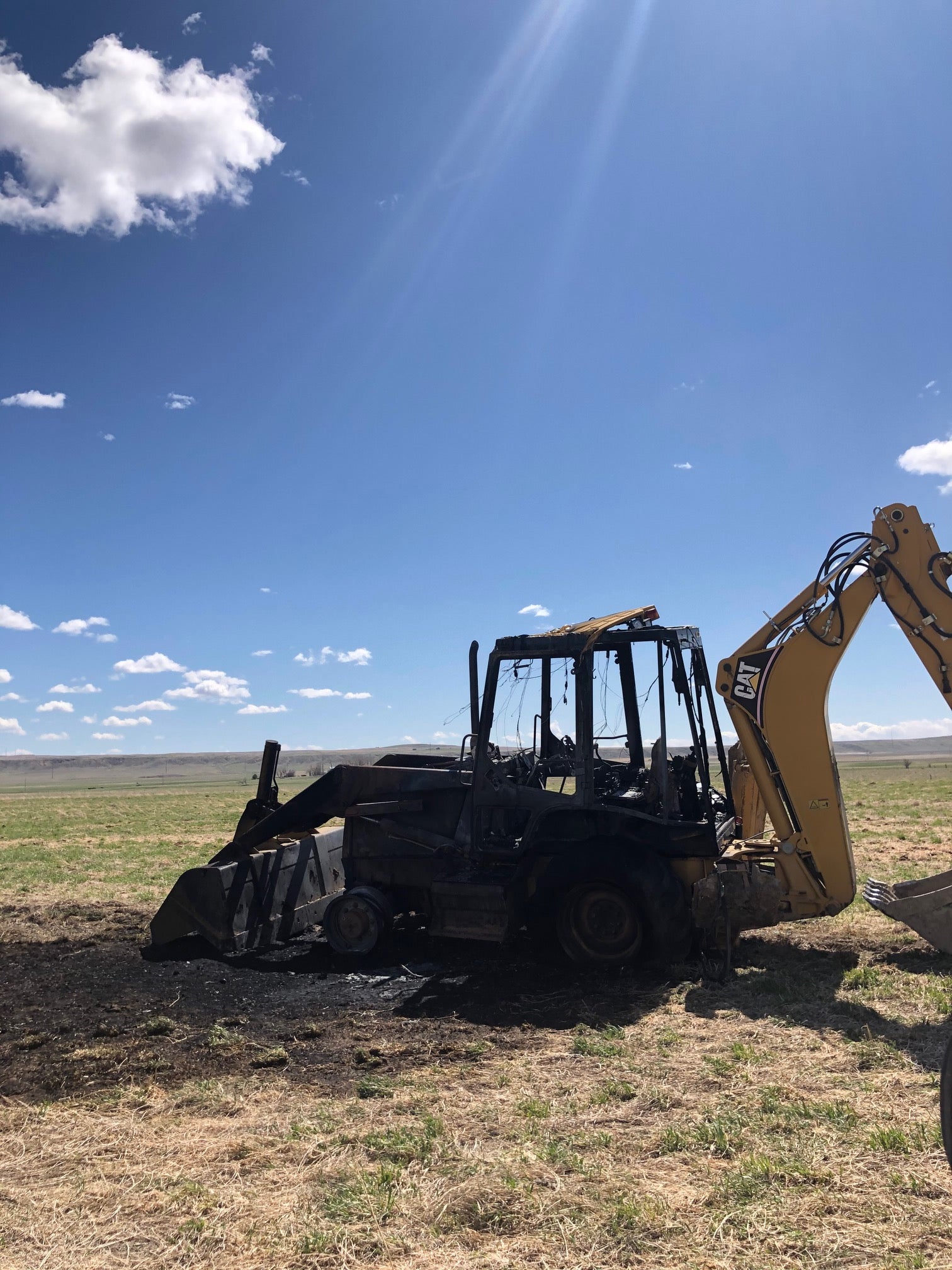 a burnt up back hoe in a field
